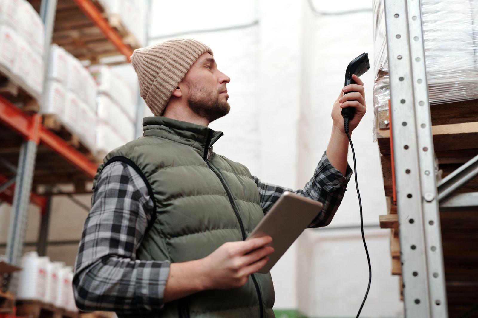 A warehouse team member scanning inventory with a handheld scanner and tablet